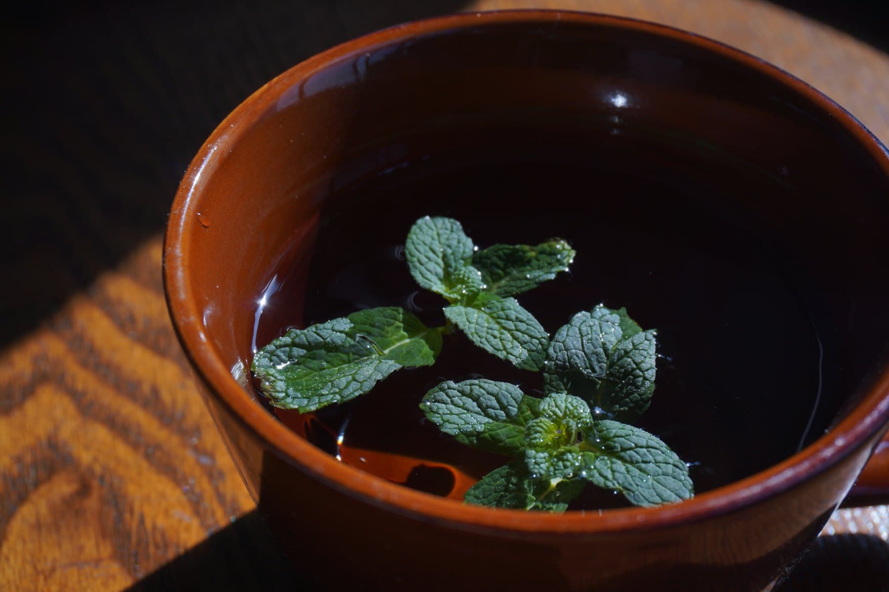 A glass cup of water infused with fresh mint leaves